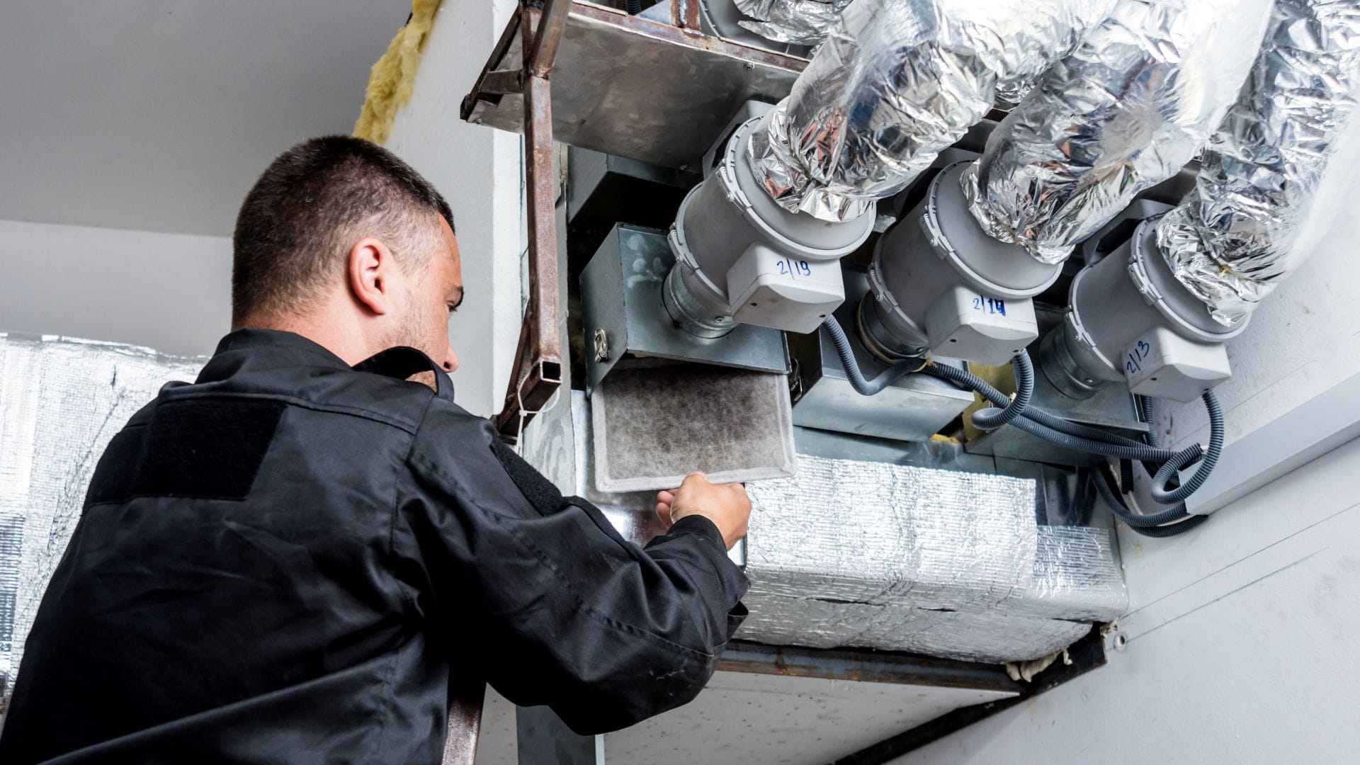 Technician inspecting a duct filter during a maintenance visit