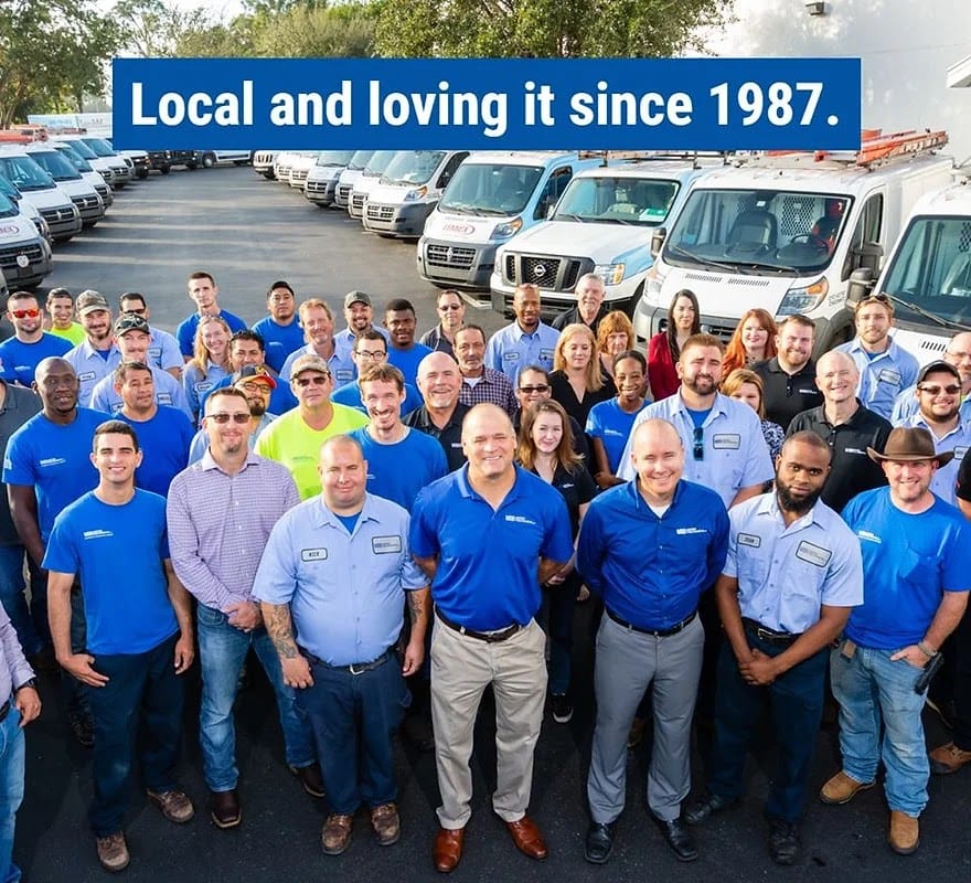 The full Advantage Heating & Air Conditioning team standing in front of their service van fleet — local and family-owned since 1987.
